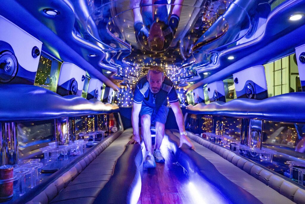A man moves through a mirrored party bus glowing electric blue.