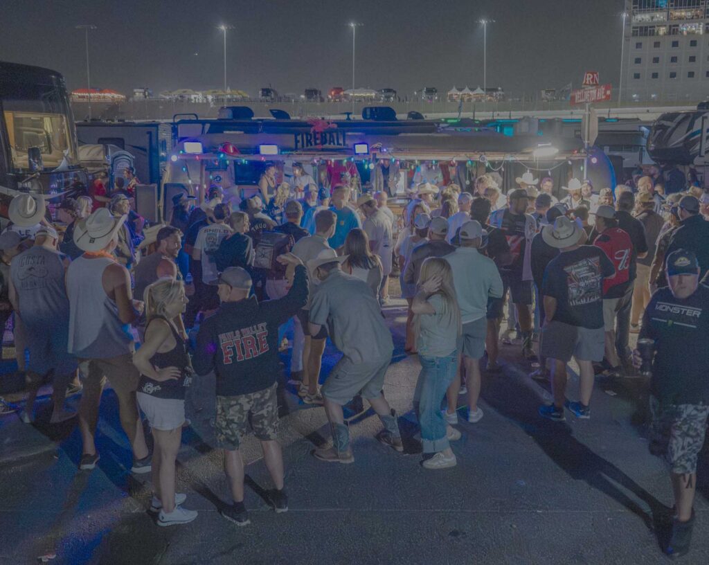 Campers crowd around an illuminated infield bar after dark.