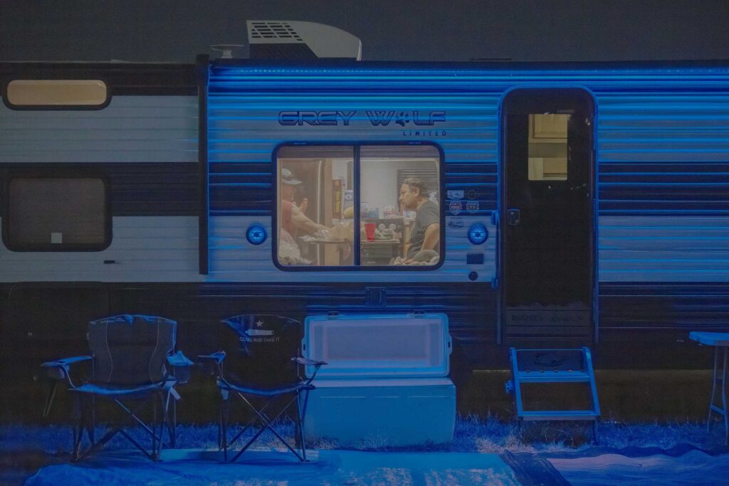 A late-night conversation glows inside a camper.