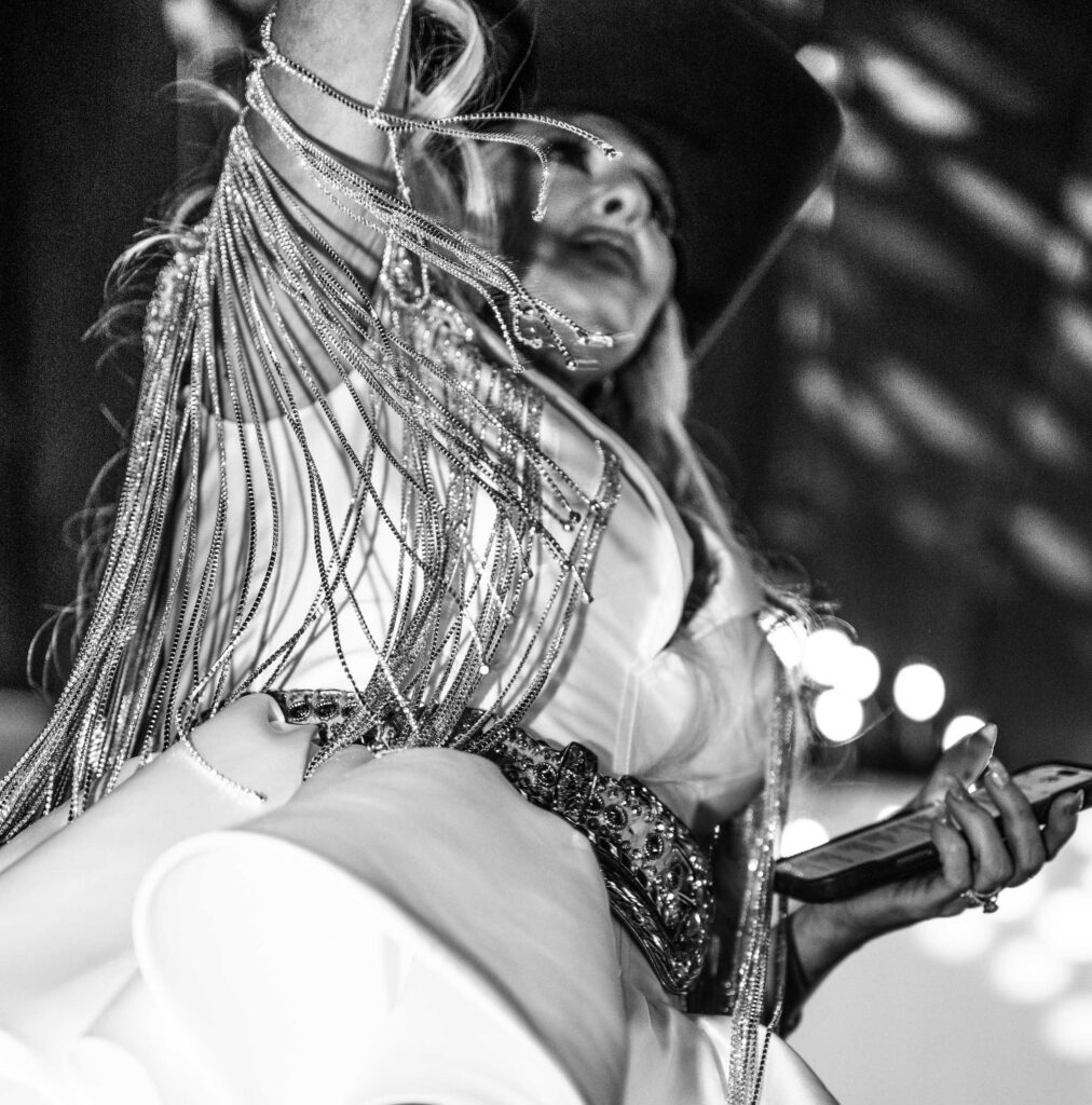 A dancer’s hat and fringe sweep across a black-and-white frame.