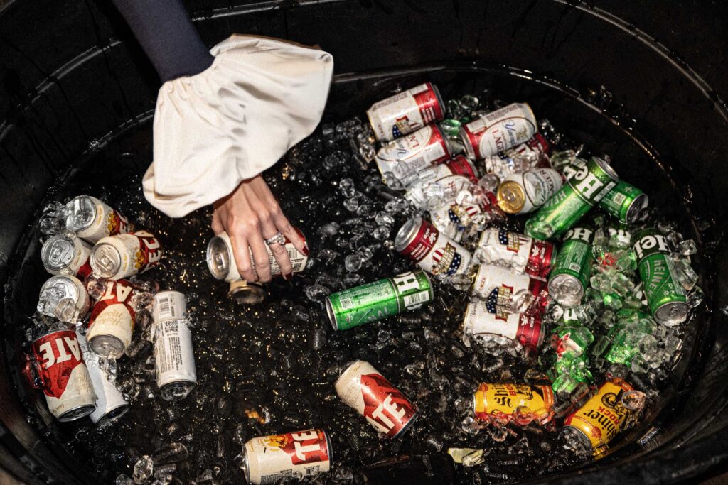 Cans of cold beer wait in an ice-filled metal trough.