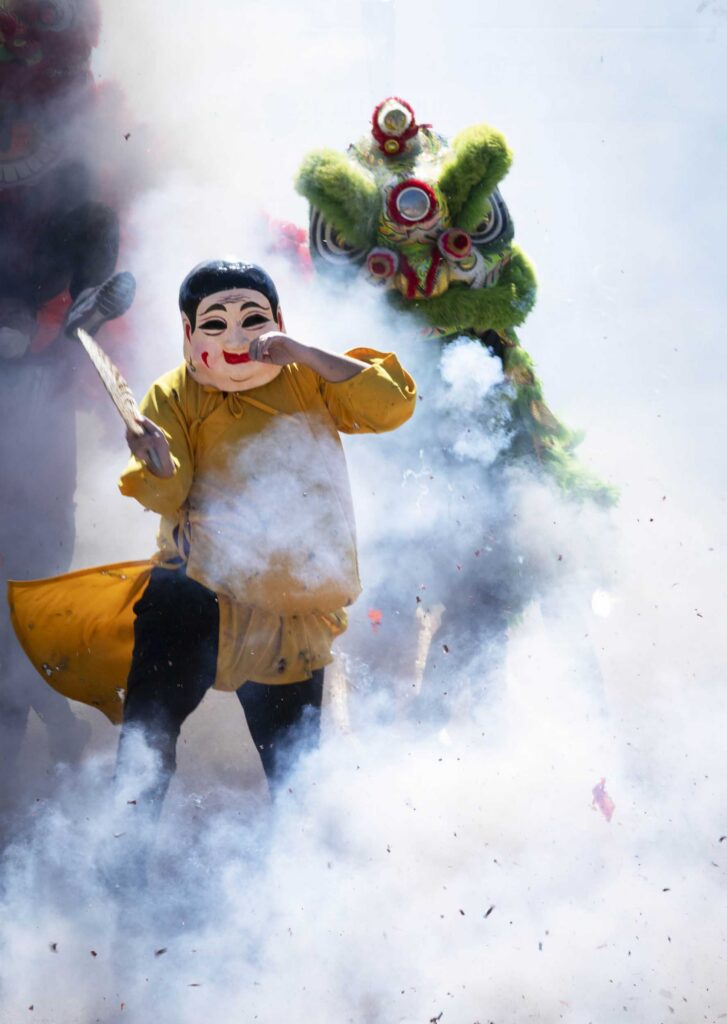 Dai Tou Fo leads a green lion through the smoke.