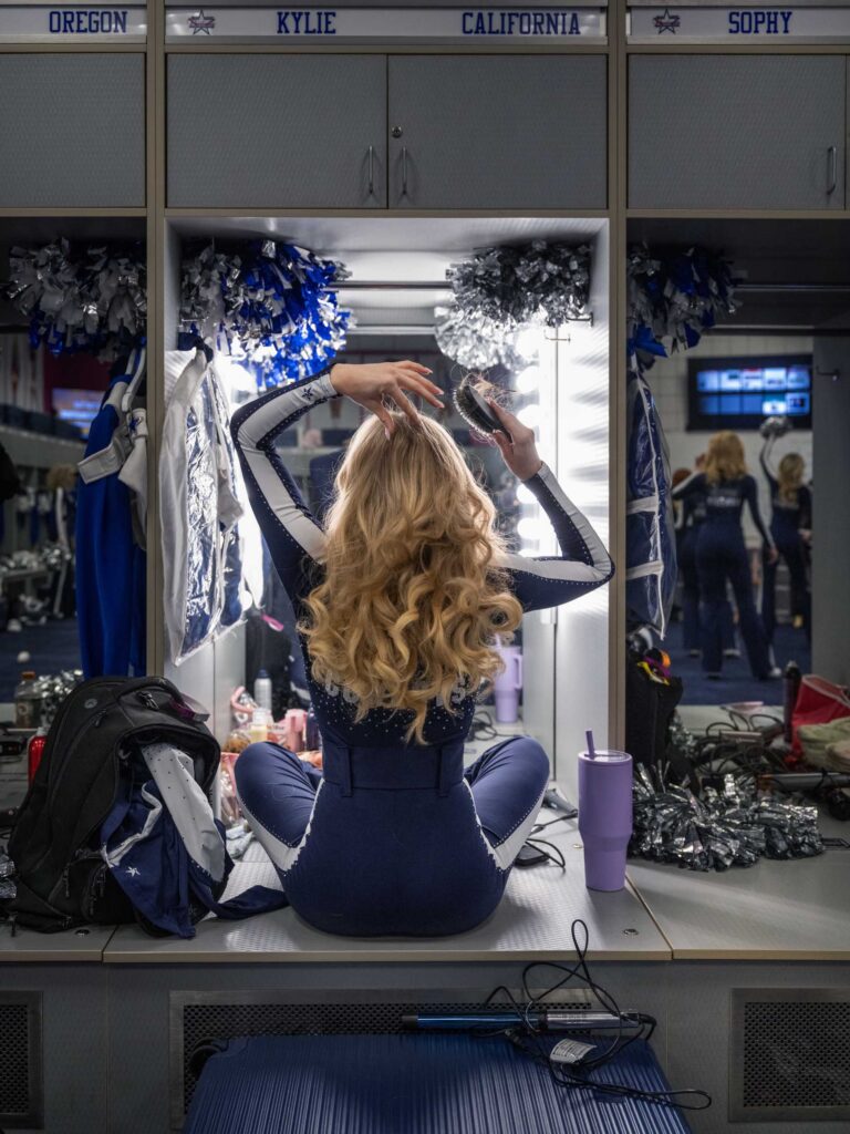 A cheerleader brushes her hair at her locker.